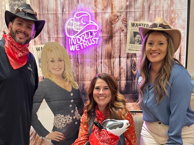Three people in cowboy hats posing for a picture with a Dolly Parton cutout