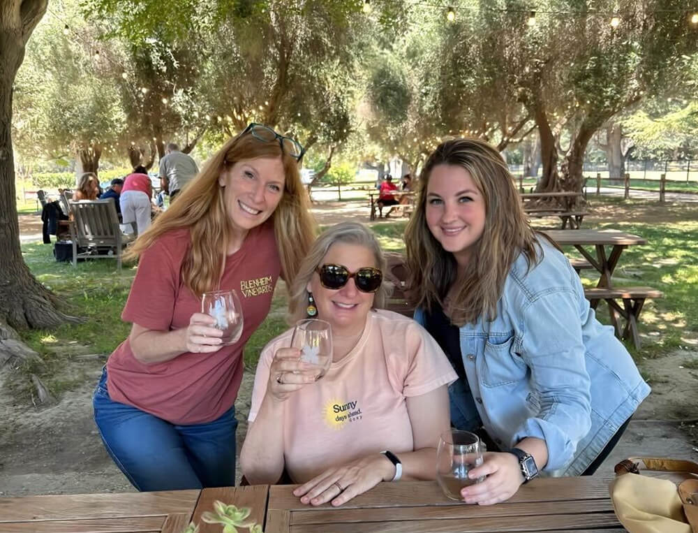 Three women enjoy drinks in the park