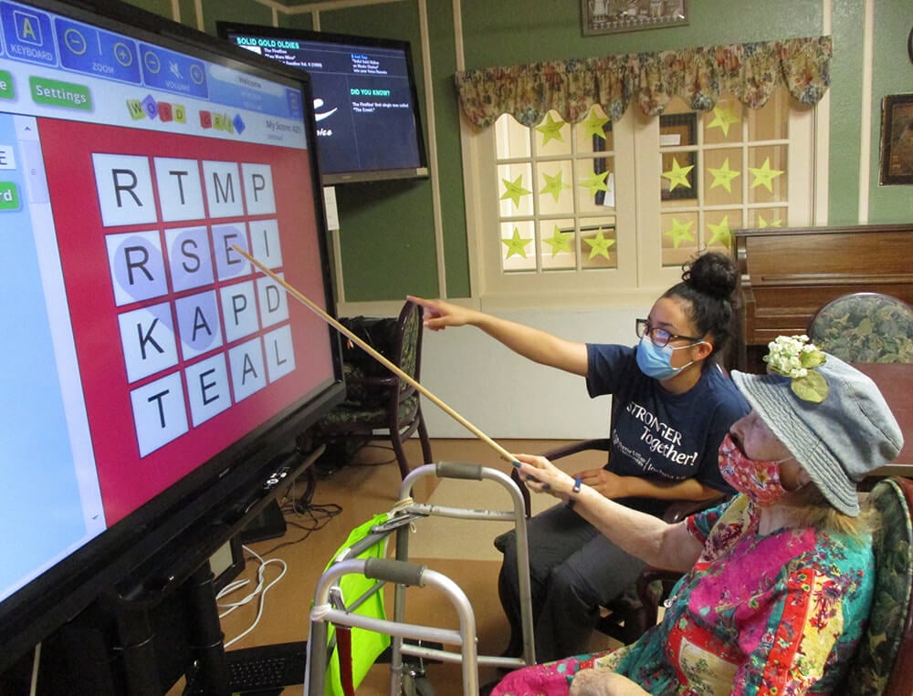 Two women play a word game on a giant screen