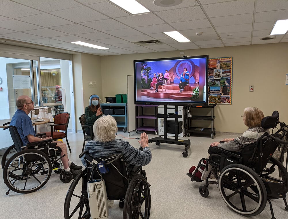 A group gather around their TV set